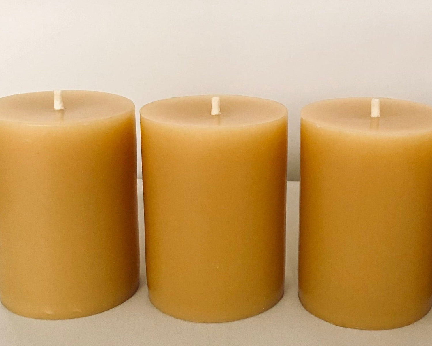 Three beeswax candles on a white background